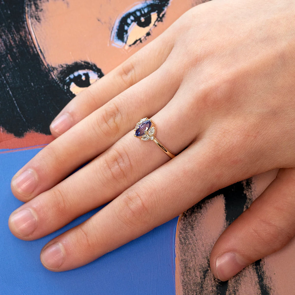 Close-up of a hand wearing a marquise purple sapphire and diamond ring, delicate and elegant.