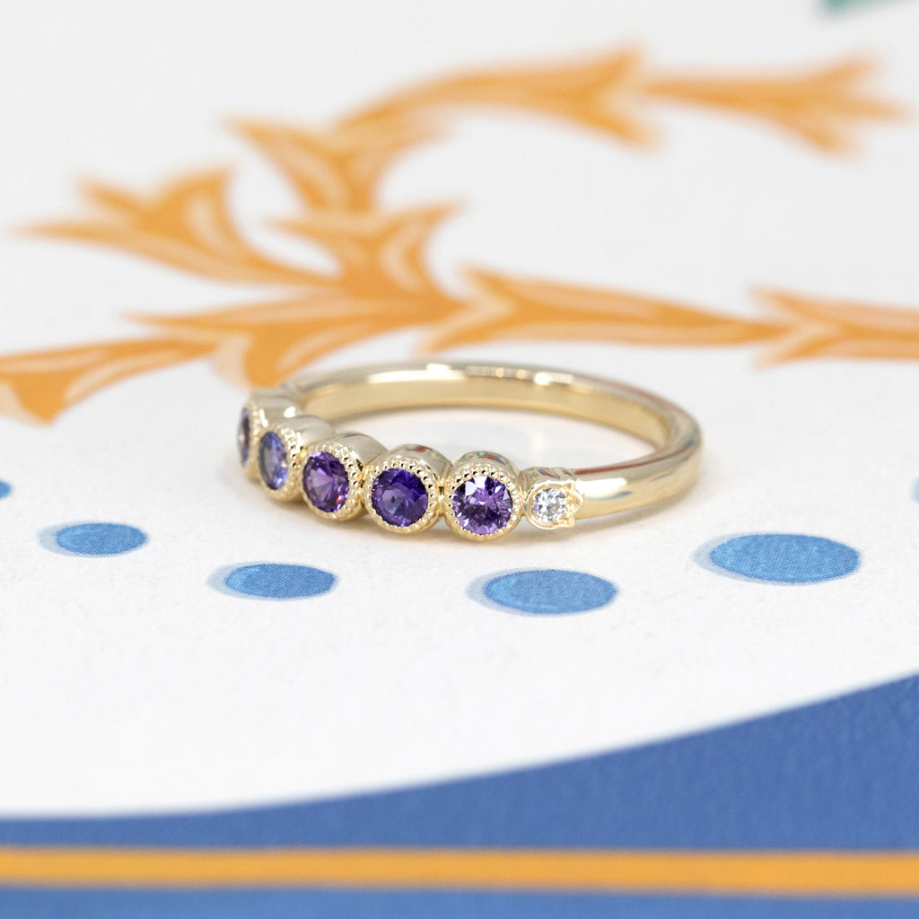 Express your eternal love with this half-eternity wedding band, enhanced by natural purple, pink and purplish sapphires, delicately mounted on yellow gold. Designed in Canada by renowned independent designer Bramston Goldsmithing, each sapphire symbolizes a precious moment. Available at Ruby Mardi of Montreal, the destination for unique, handmade bridal jewelry.