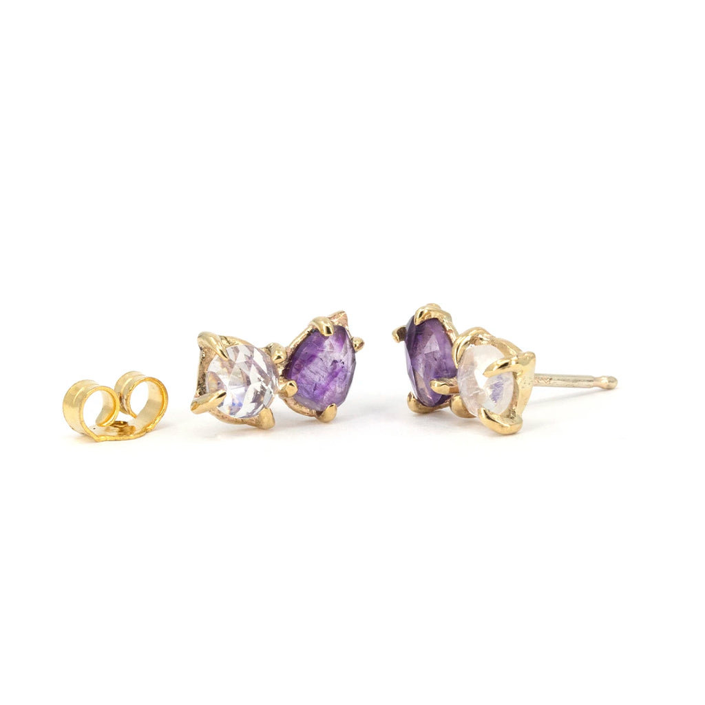 10k yellow gold stud earrings by Toronto independent designer Nadia Werchola, featuring natural amethyst and rose-cut moonstone in slightly irregular eagle-claw prong settings, shown with matching gold backs on a white background, available at Ruby Mardi in Montreal.
