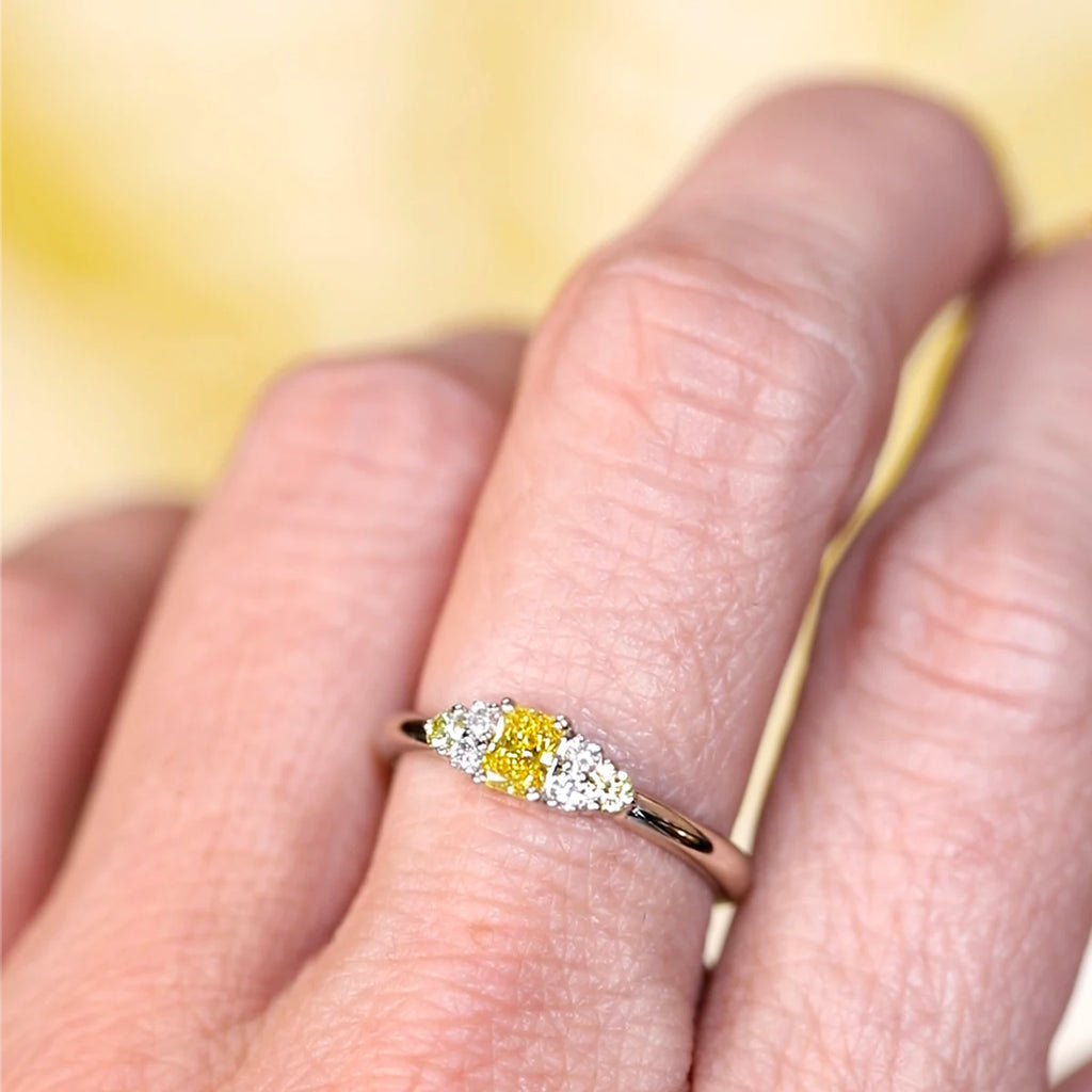 Radiant yellow lab-grown diamond ring with canary yellow and white diamond accents in 10k white gold, worn on a hand – Ruby Mardi Montreal.