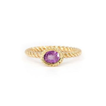Gold ring with twisted band and bezel-set oval opalescent pink sapphire, featuring rope detailing. Raspberry Jam ring by In the Light of Day Jewelry, available at Ruby Mardi in Montreal.