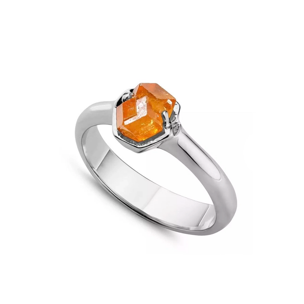 Bird’s eye view on a white background of a designer ring in 10k white gold ring featuring a big orange raw gemstone. 