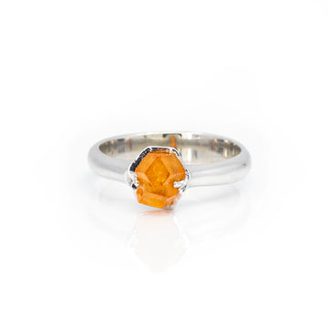 Front view of a white gold statement gender fluid ring featuring a big raw orange gesmtone. This one-of-a-kind ring was handmade in Montreal by independent jewelry designer François Charest. An alternative engagement ring seen photographed on a white background.
