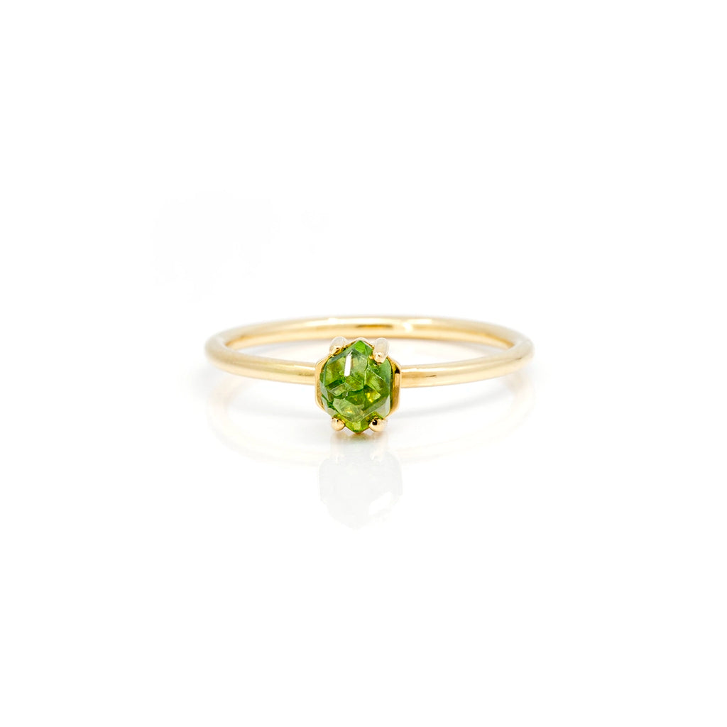 Yellow gold ring featuring a green gemstone from Quebec : a raw gemstone garnet. This alternative solitaire engagement ring or delicate right hand ring was handcrafted in Montreal by jewelry designer François Charest. It is seen on a white background.
