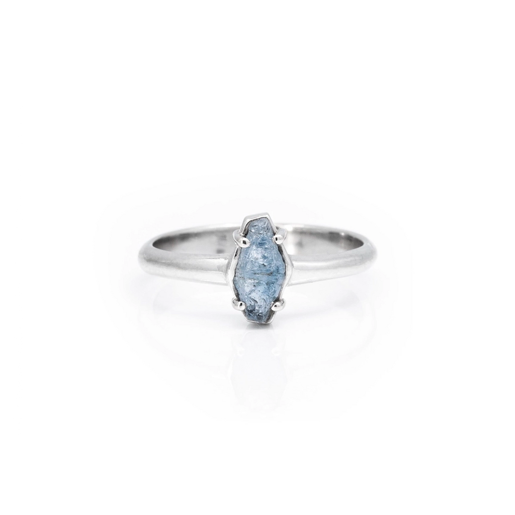 Front view of a one-of-a-kind alternative bridal ring featuring a blue-grey raw sapphire bezel set in white gold. This dainty ring is flat on the finger and is an original design from Montreal jeweller François Charest. 
