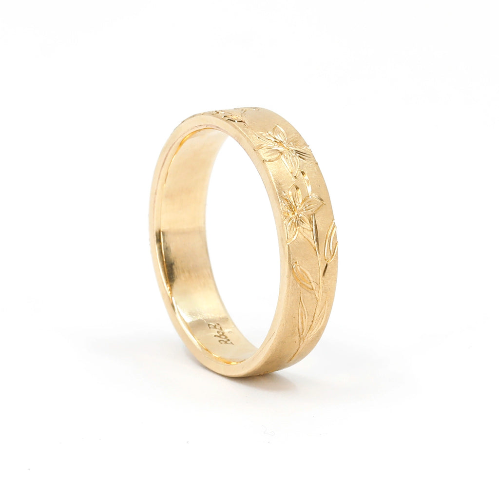 Hand-engraved floral 14k gold band with matte finish by Rebel & Rogue, photographed on a white background for Ruby Mardi in Montreal, Canada. The intricate flower and leaf engravings emphasize the romantic, boho-inspired craftsmanship of this artisan wedding ring.