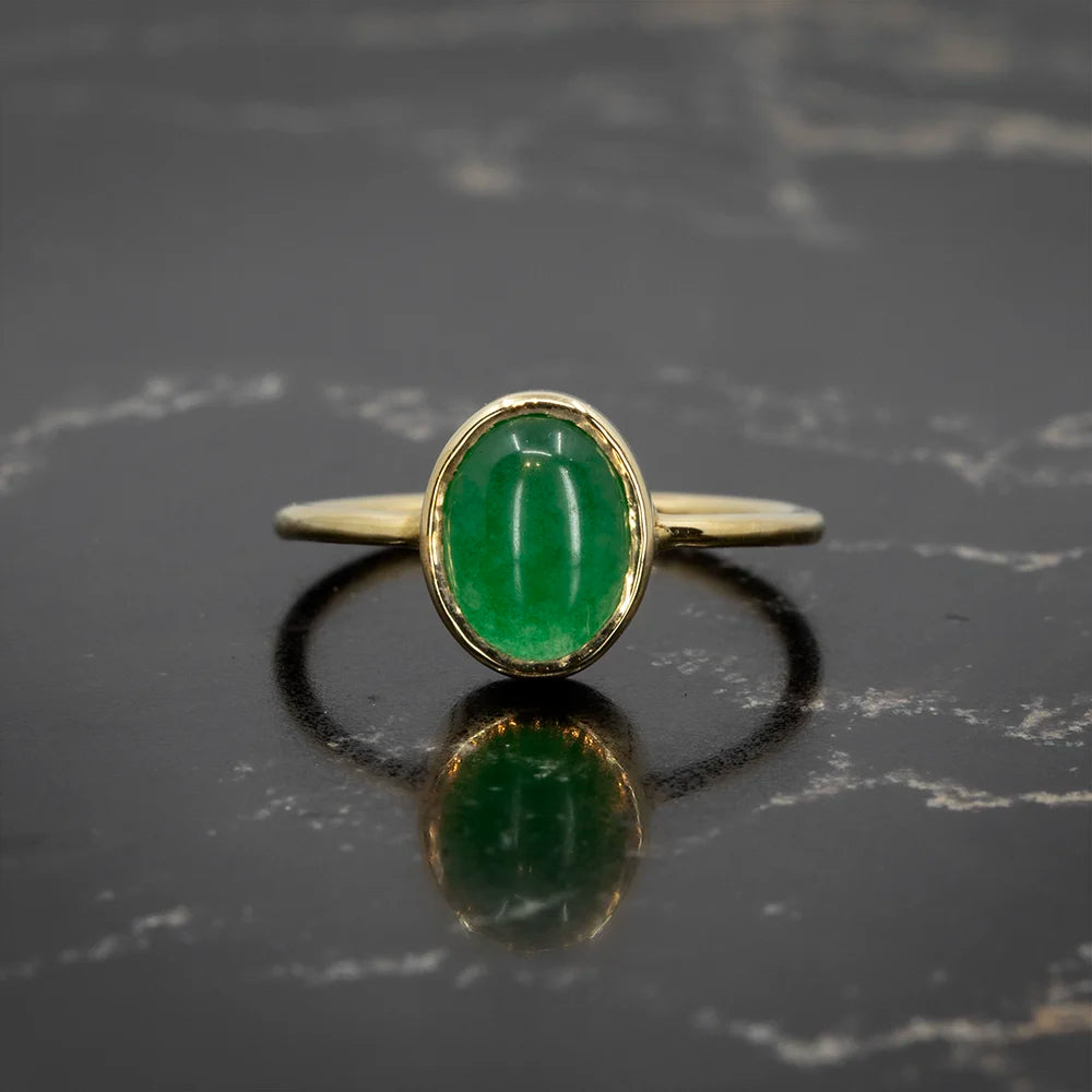 Yellow gold ring by Rooz Jewellery, showcasing a captivating oval jade cabochon in a simple bezel setting. Available at Ruby Mardi, Montreal.