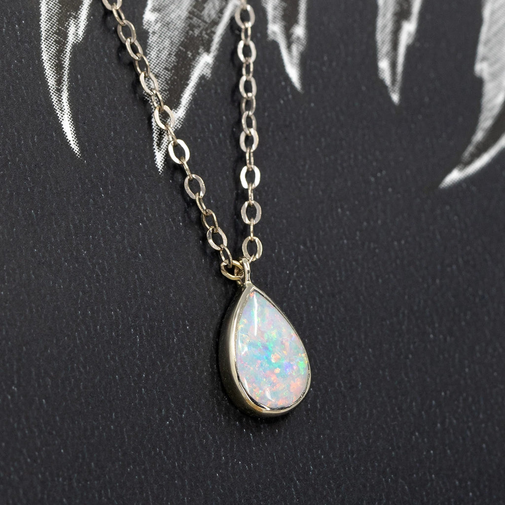 White opal pendant bezel set in solid white gold and photographed on a black and white background. This classic jewelry piece was handcrafted in Toronto by independent designer Rooz Jewellery, and is available at the best jewelry store in Canada, Ruby Mardi.