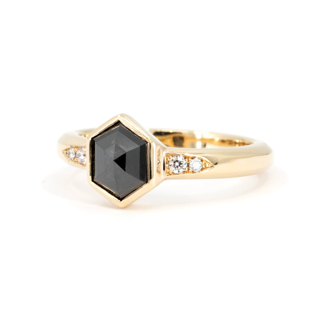Fashion engagement ring featuring a hexagonal rose cut black diamond set in 14k yellow gold with natural round brilliant diamond accents. This modern bridal jewelry piece was handmade in Toronto by designer Yuliya Chorna. It's a one-of-a-kind ring that is only available through Ruby Mardi, the best jewelry store in Montreal, Canada.