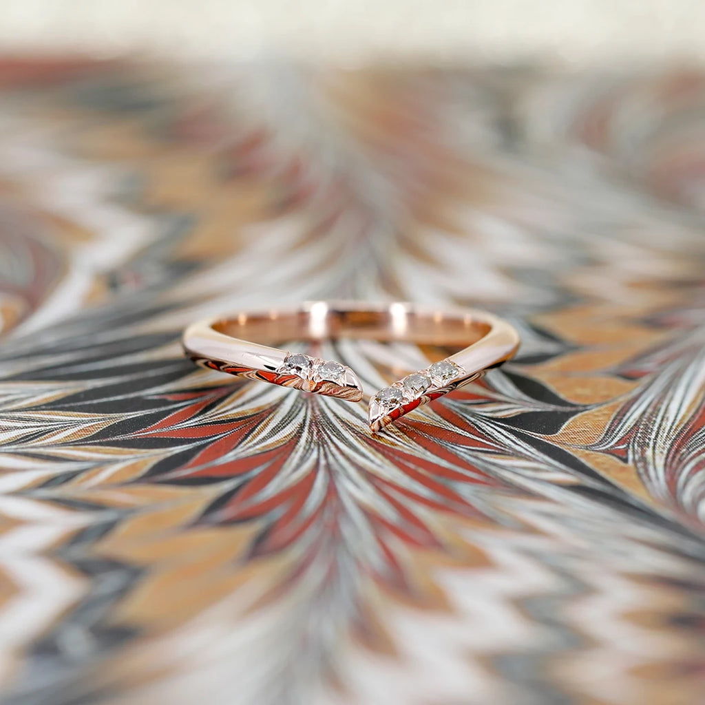 A psychedelic picture showing a rose gold open ring with brown diamonds. The wedding band is photographed on a funky background.