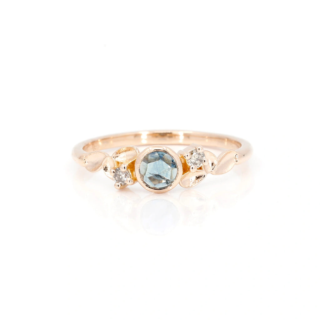 This splendid and delicate engagement ring is made in gold with a light blue colored rose cut sapphire. This bridal jewelry is made by independent Montreal jewelry designer Emigé. Made in 18 kt with a Montana sapphire, this ring is a custom creation available at Ruby Mardi, the best jewelry store in Montreal.