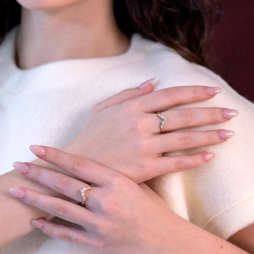 Close-up of hands adorned with elegant crown-shaped diamond wedding bands in yellow gold. The delicate, wavy design is perfect for stacking or wearing individually. Made by Ruby Mardi in Montreal.