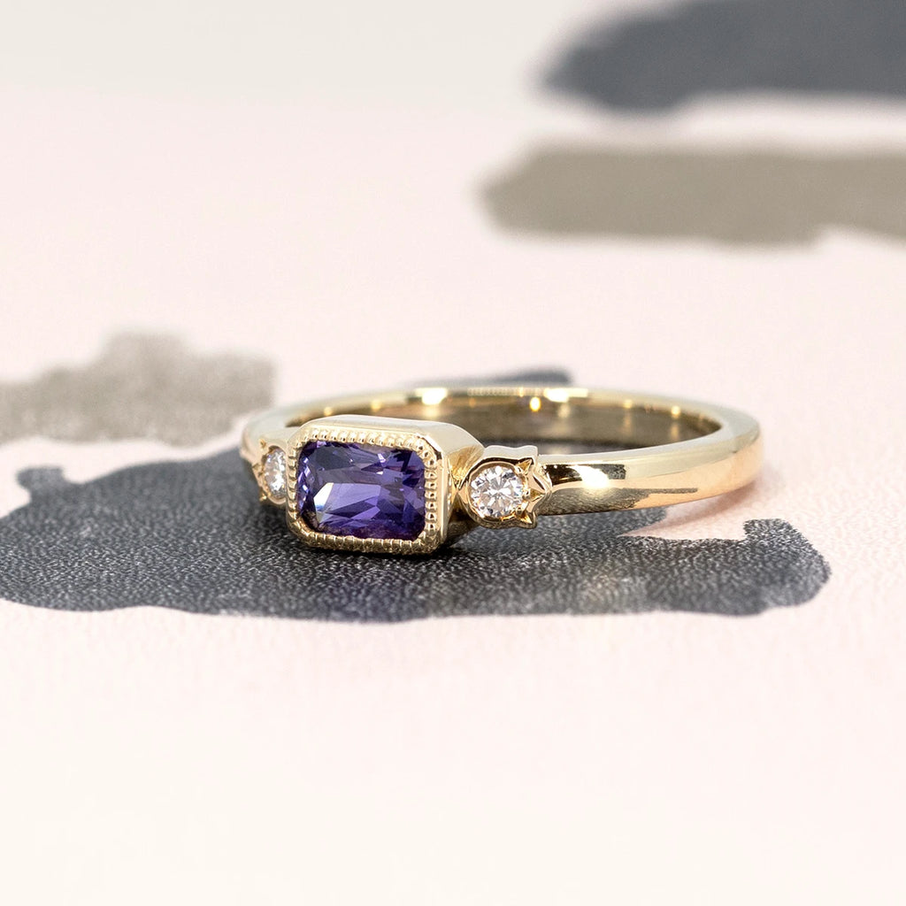 Discover exclusivity with this stunning Canadian purple sapphire engagement ring, set in yellow gold and adorned with two side diamonds. An artistic creation from Bramston Goldsmithing that reflects expertise and refinement. Every carefully crafted detail evokes the exceptional quality of this ring. A limited edition born from the collaboration between Bramston Goldsmithing and Ruby Mardi, the renowned Montreal jewelry store specializing in alternative engagement rings.