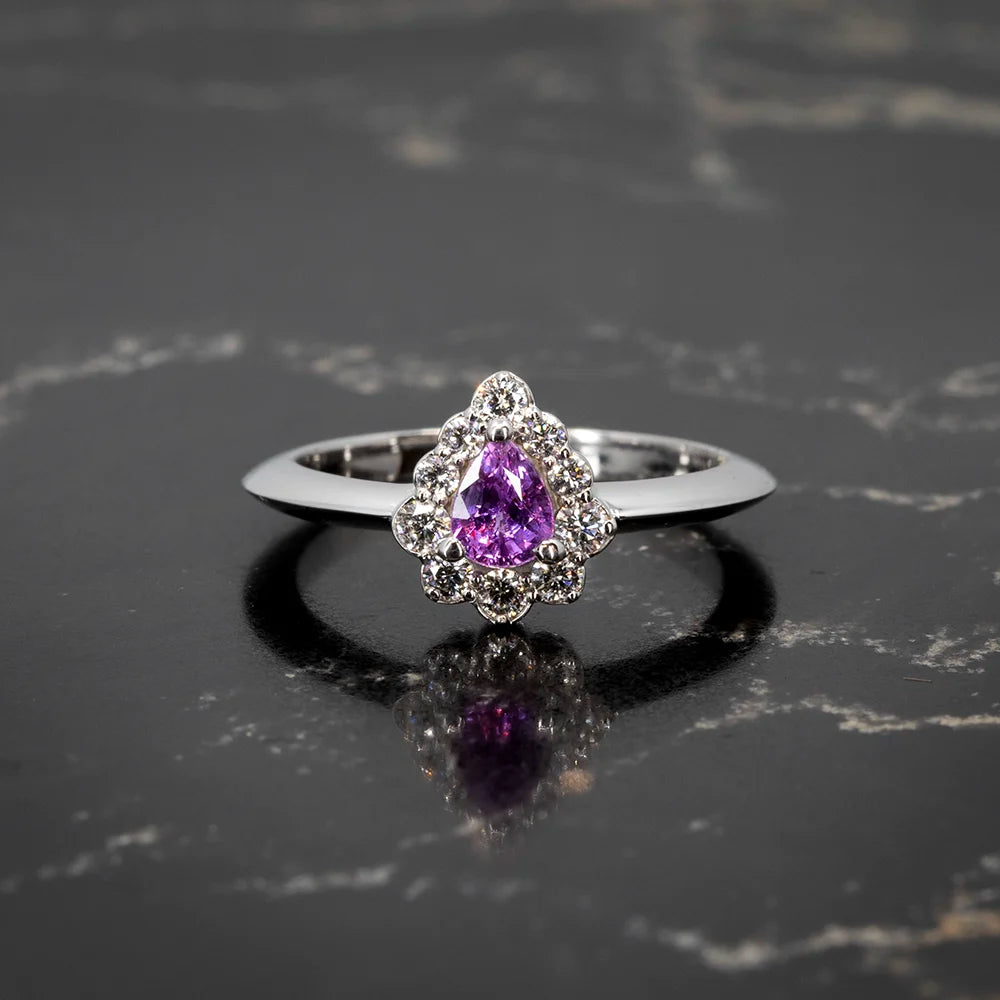 A stunning pear-shaped purple sapphire halo engagement ring in white gold, accented with sparkling diamonds. Available exclusively at Ruby Mardi, Montreal's fine jewelry destination.