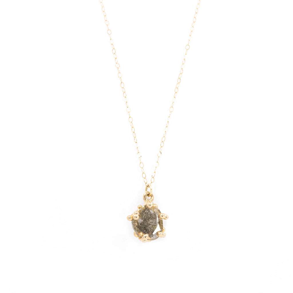 Close-up of a unique necklace featuring a 16-inch thin gold flat cable chain adorned with a flat slice salt & pepper diamond pendant. Designed by artist Meg Lizabet, the pendant showcases an organic style with handmade prongs resembling gold granules. This funky one-of-a-kind piece is exclusively available at Ruby Mardi.