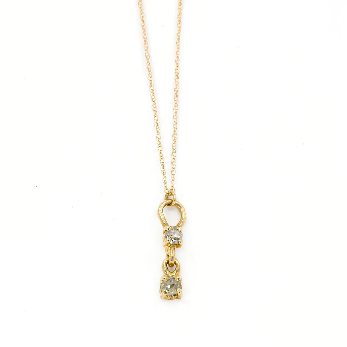 10k yellow gold pendant featuring two round salt-and-pepper diamonds, designed with an organic, handcrafted look by Nadia Werchola. The lower diamond is suspended from the upper one, allowing it to dangle when worn. Photographed on a white background.