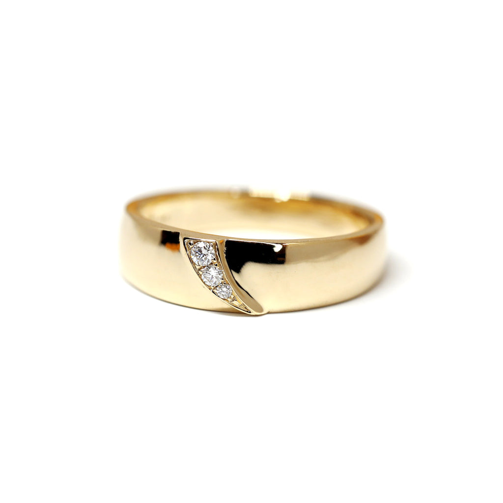 A wide yellow gold wedding band with diamonds on a shooting star shape, created by toronto-based jewelry designer Yuliya Chorna and photographed on a white background.