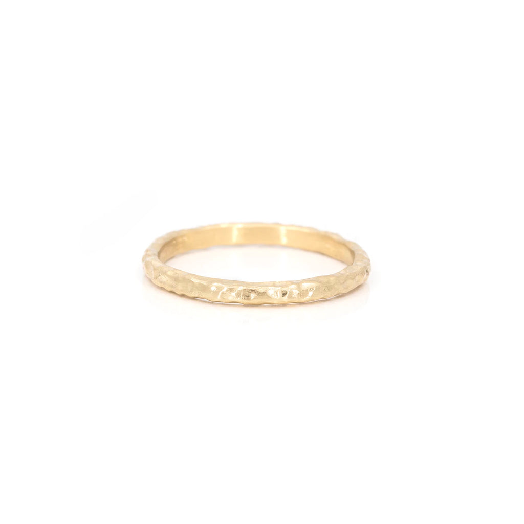 Extra fine handmade gold wedding band showing a textured and seen photographed on a white background. This yellow gold ring is available at fine jewelry store Ruby Mardi in Montreal, and was handcrafted by Anouk Jewelry, an independent brand.