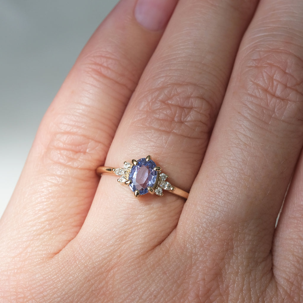 Sky blue sapphire and diamond engagement ring worn on hand, set in 14k yellow gold. Handmade by Maksym Jewelry, available at Ruby Mardi in Montreal, Canada.