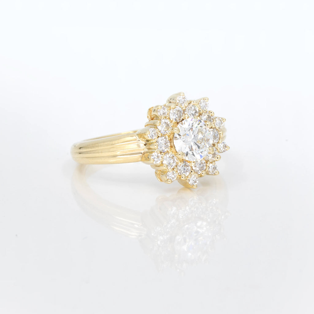 All-diamond ring in yellow gold with a lot of lab grown diamonds forming a sun shape : one central oval diamond and twenty small round brilliant diamonds all around the center one. This beautiful and original piece of jewelry was designed by fine jewellery store Ruby Mardi in Montreal. It is seen photographed from the side, on a white background.