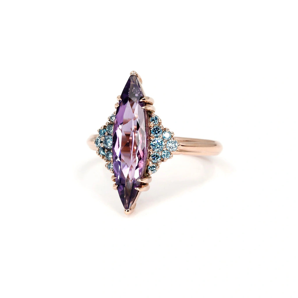 Large marquise-cut amethyst ring with clusters of blue diamond accents in a rose gold setting – bold statement jewelry by Bena Jewelry, Ruby Mardi Montreal.