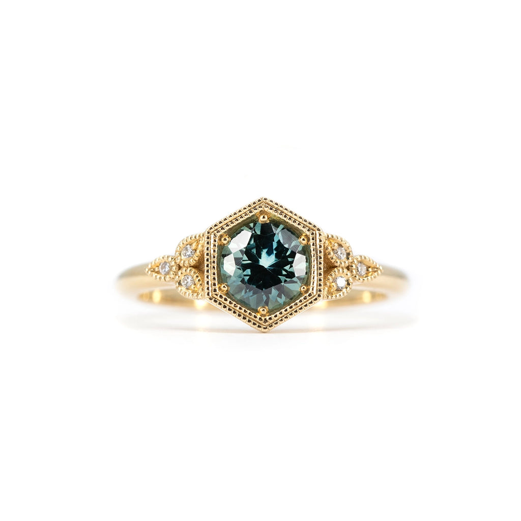 Hexagonal vintage-inspired engagement ring with teal sapphire center stone, diamond accents, and yellow gold band, designed by Emily Gill, available at Ruby Mardi, Montreal Canada.
