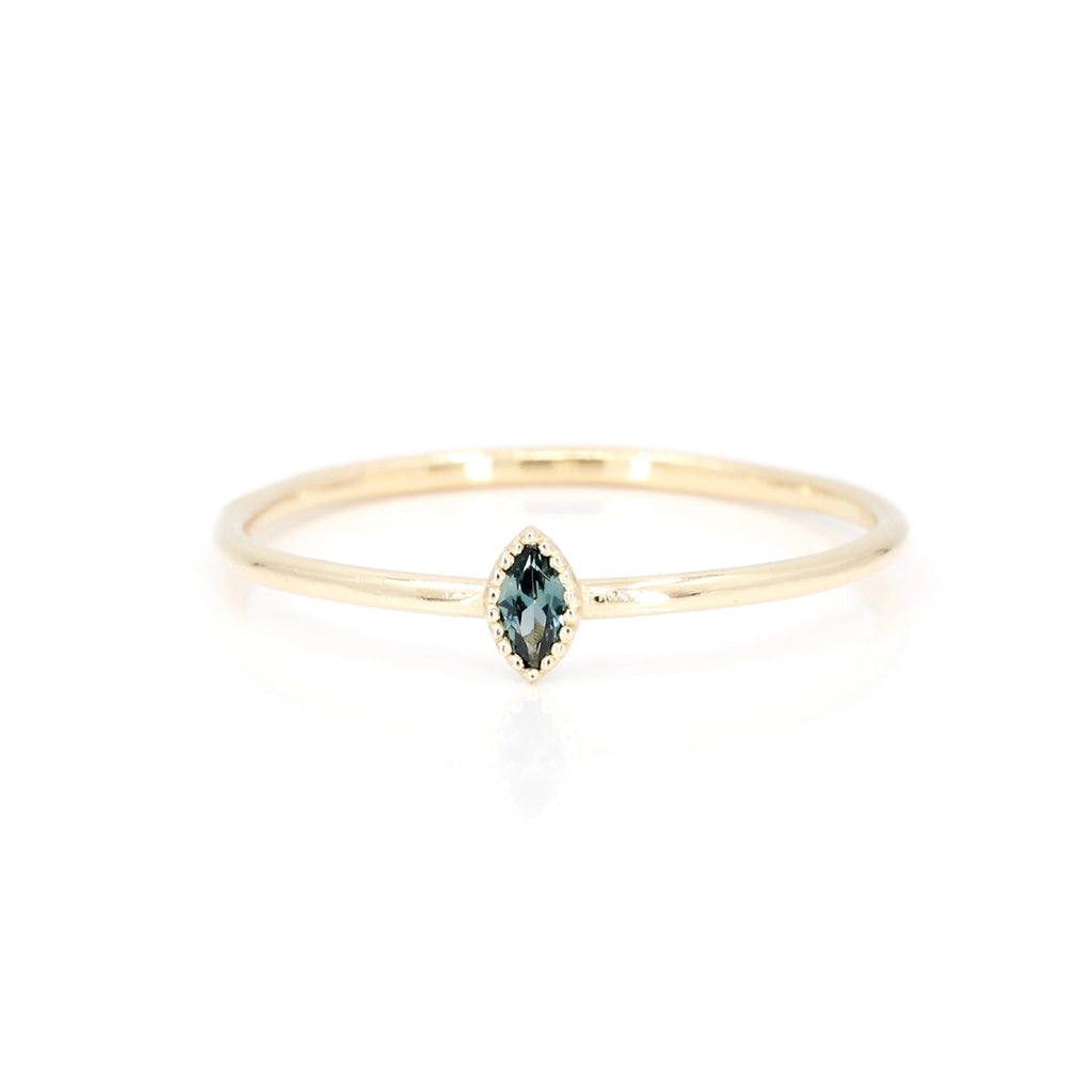 This small engagement ring is delicate and made in Montreal in yellow gold with a small marquise-shaped blue sapphire. Created by independent jewelry designer Émigé, this alternative bridal jewelry is a custom creation available for sale at Ruby Mardi, the best jewelry store in Quebec.