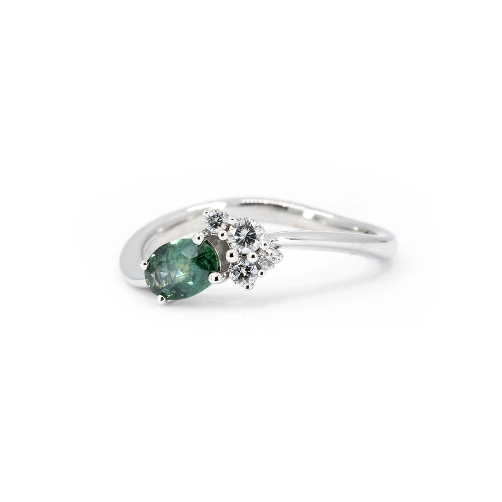 Twisted band engagement ring in white gold featuring an oval green-blue Montana sapphire and a cluster of four round diamonds, designed by Justine Quintal for Ruby Mardi, made in Montreal, Canada.