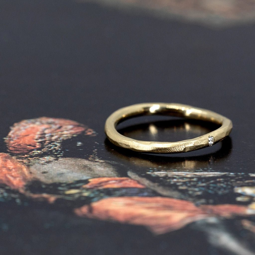 A twisted, organic 2mm gold band featuring a small diamond accent, designed and crafted by Sheena Purcell, available at Ruby Mardi, a unique jewelry store in Montreal.