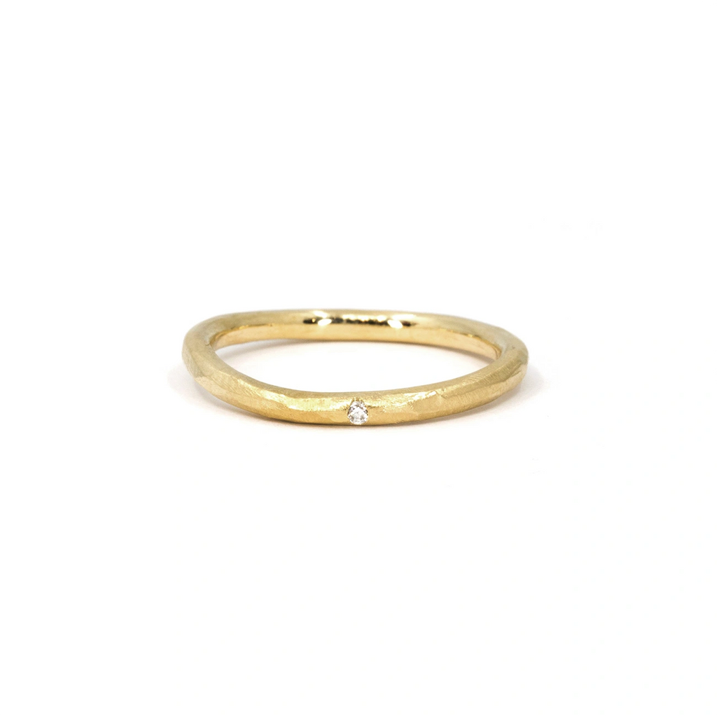Organic gold band with a subtle twisted shape and a single flush-set diamond. Handcrafted with a textured finish, this unique wedding or stacking ring is available at Ruby Mardi, a Montreal-based designer jewelry store.