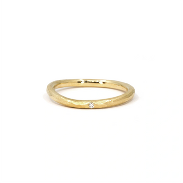 Organic gold band with a subtle twisted shape and a single flush-set diamond. Handcrafted with a textured finish, this unique wedding or stacking ring is available at Ruby Mardi, a Montreal-based designer jewelry store.