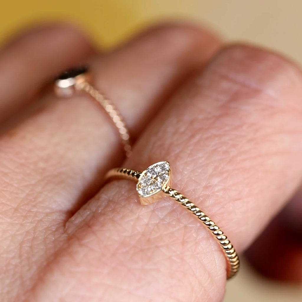 Close-up of the Alizé ring by Oleg Leybman, worn on a finger. Features a vertical marquise-shaped cluster of natural white diamonds on a twisted 14k yellow gold band. Handcrafted in Toronto, available at Ruby Mardi.
