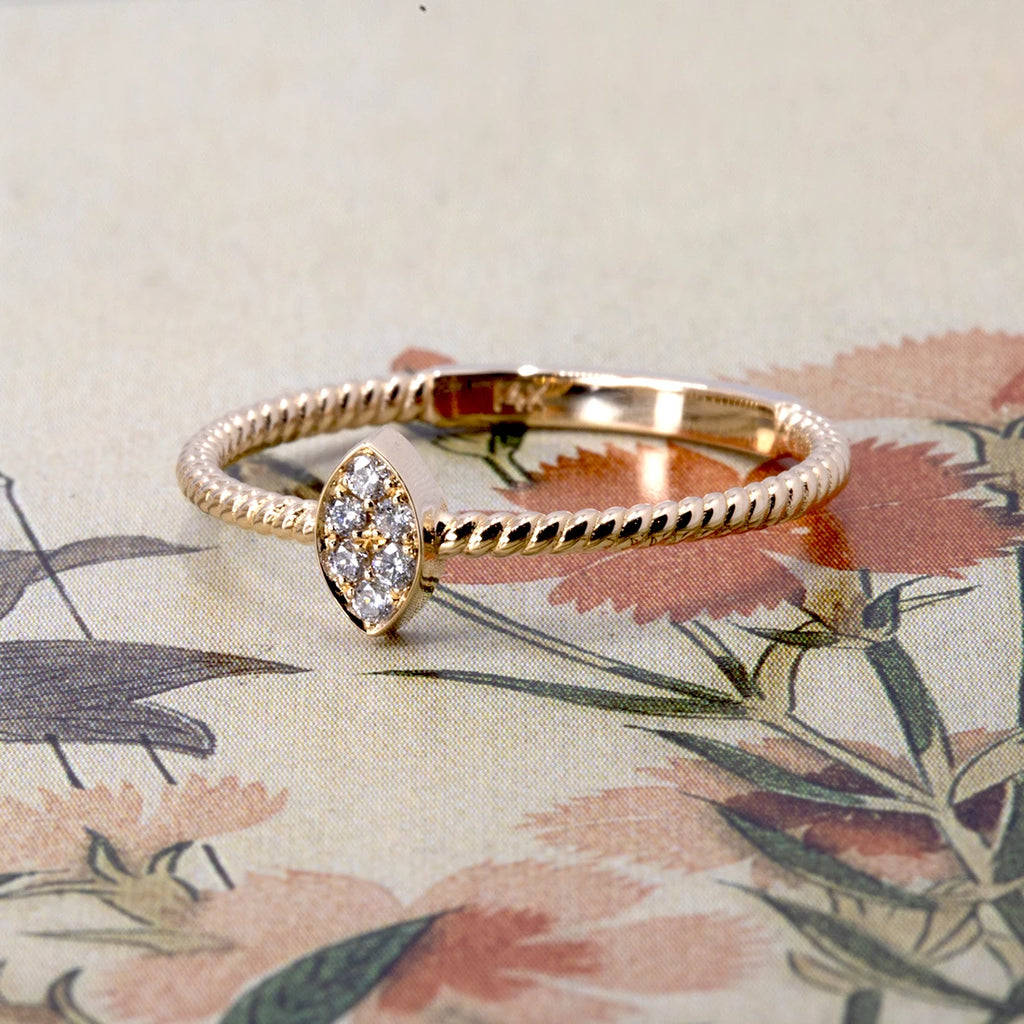 Alizé ring by Oleg Leybman, featuring a marquise-shaped cluster of natural white diamonds on a twisted 14k yellow gold band. Photographed on vintage floral background. Handcrafted in Toronto, available at Ruby Mardi.