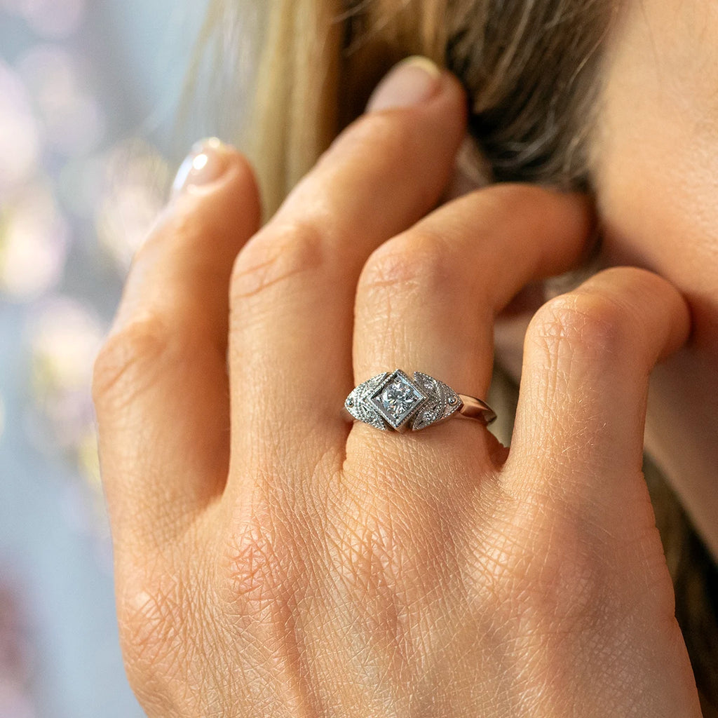 Ruby Mardi engagement ring – 14k white gold Art Deco inspired ring designed by Deborah Lavery, shown worn on the hand. Featuring a central round diamond set in a geometric square frame with intricate milgrain and pavé diamond details. Vintage-style bridal jewelry available at Ruby Mardi.