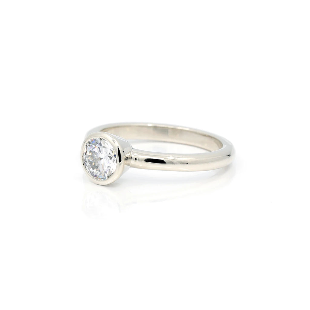 Splendid alternative and unique engagement ring is created and manufactured in Canada by independent jewelry designer Janine de Dorigny. This minimalist bridal jewelry is made in white gold with a bezel setting to give it a discreet and original style. Available for sale at Ruby Mardi, the best atypical bridal jewelry store in Quebec and located in Montreal.
