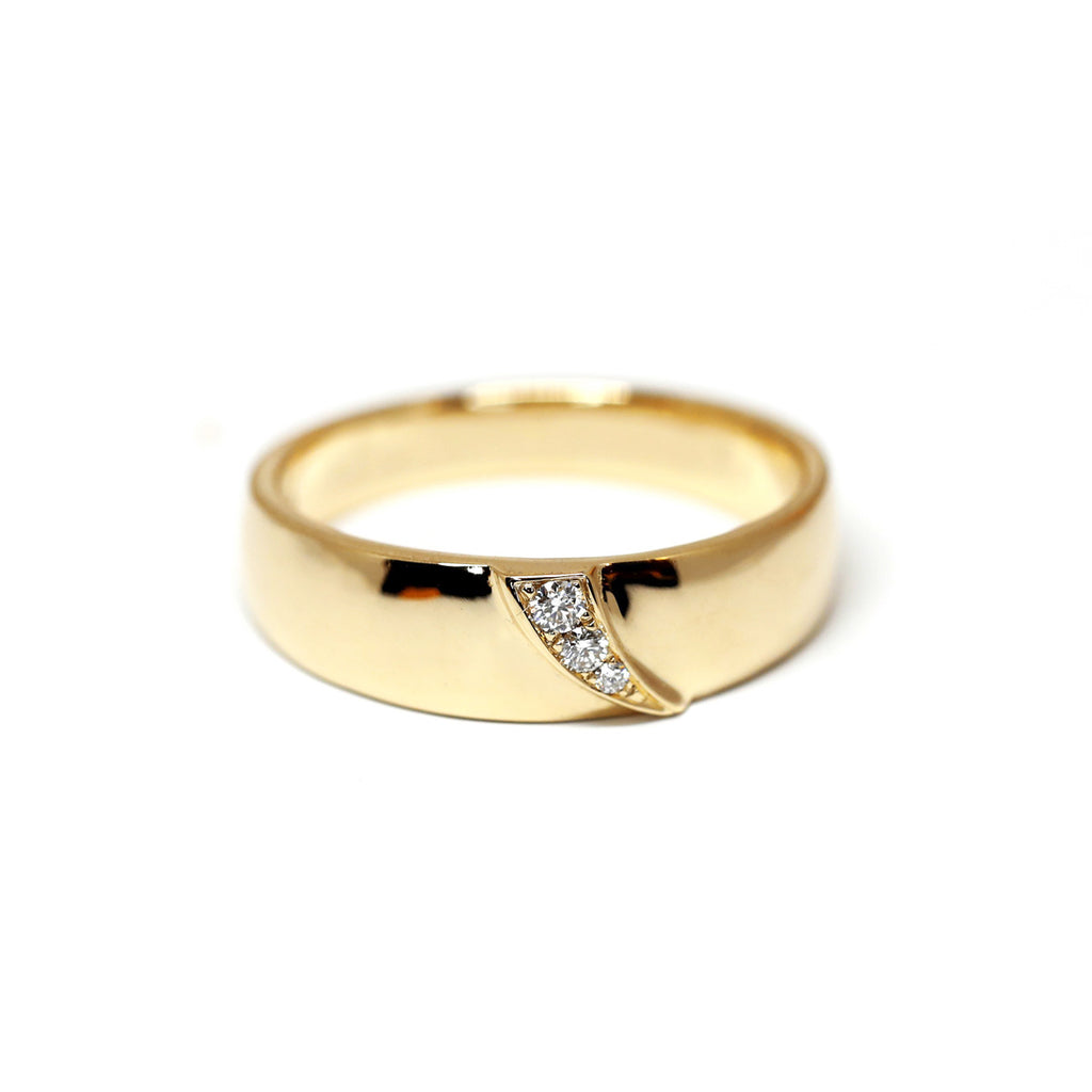 A wide yellow gold wedding band with diamonds on a shooting star shape, created by toronto-based jewelry designer Yuliya Chorna.