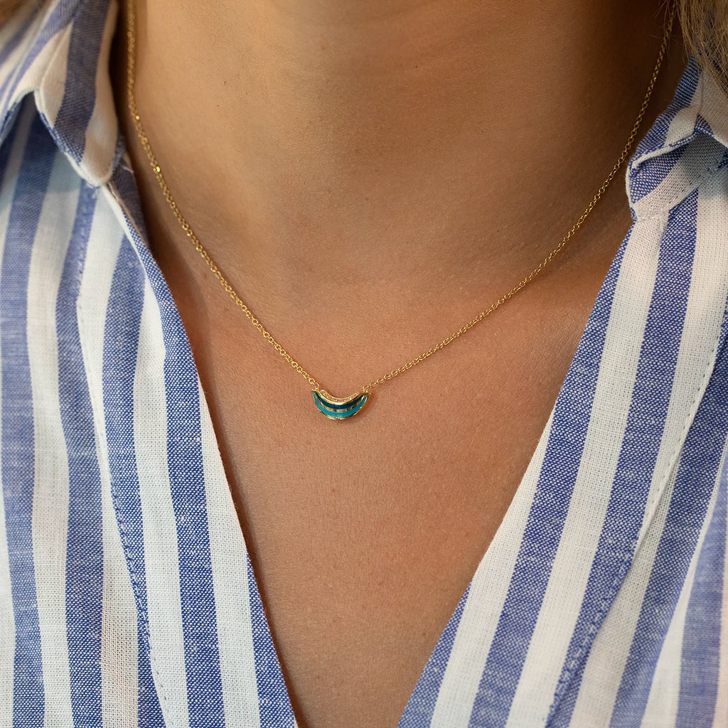 Model wearing the Emily Gill 14k yellow gold necklace with blue enamel and diamonds, available at Ruby Mardi designer jewelry store in Montreal.