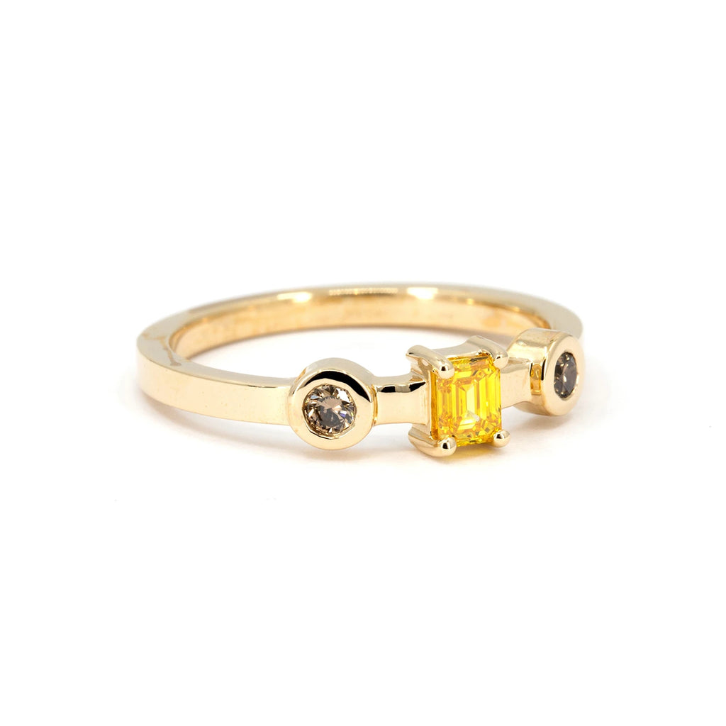  Contemporary yellow gold ring featuring an emerald-cut yellow diamond and two round natural brown diamonds in bezel settings, alternative engagement ring available at Ruby Mardi.