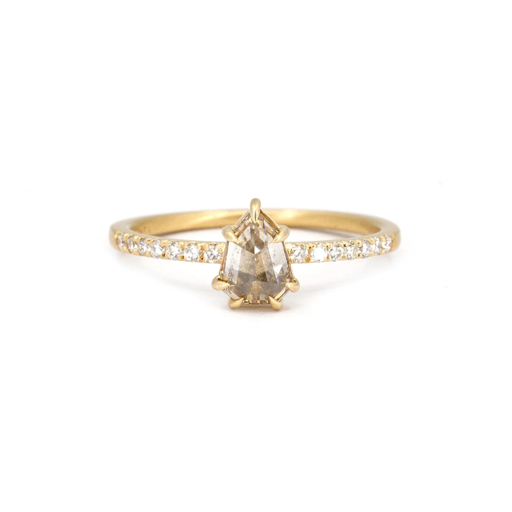 Pretty yellow gold engagement ring with a half-set diamond band is photographed against a white background. This solitaire ring features a champagne shield diamond set with eagle claw prongs. The ring was created in Ottawa by Fluid Jewellery. It is sold by Ruby Mardi, a luxury jewelry store that sells one-of-a-kind and ethical jewelry pieces.