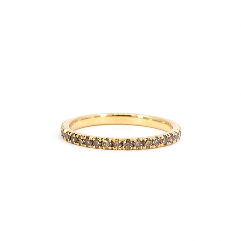 Yellow gold eternity band set with small golden diamonds in a full circle, photographed on a soft white background. Fine designer jewelry available at Ruby Mardi in Montreal.