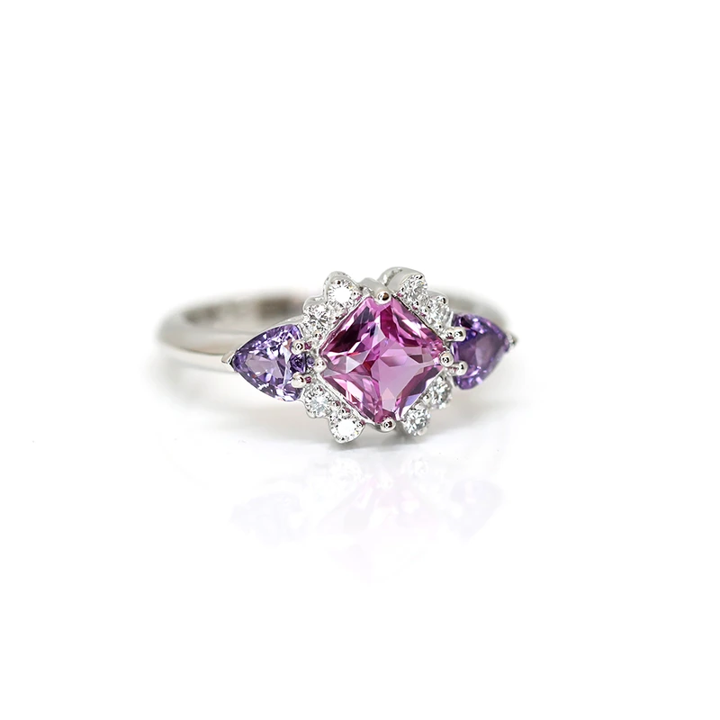Custom made platinum ring with a central pink sapphire, lateral purple trillion sapphires and diamond accents.