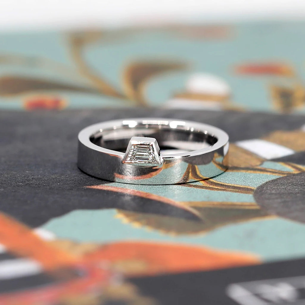 White gold ring with a splendid trapeze diamond in a bezel setting with a boxy style. Made in Canada, this contemporary piece of jewelry is a creation by independent jewelry designer Bena Jewerly in partnership with fine jewelry store Ruby Mardi of Montreal.