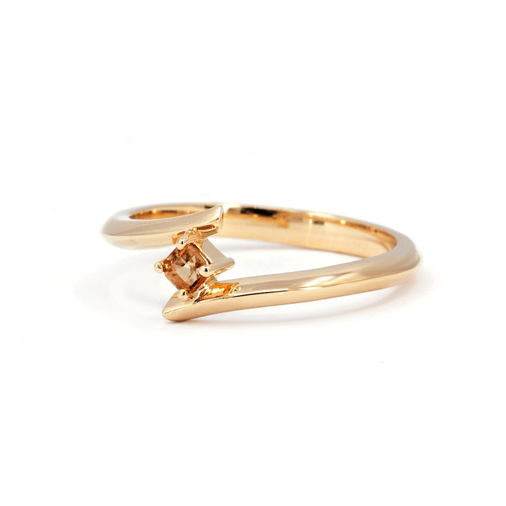 This alternative engagement ring is set with a peach orange sapphire set with yellow gold and an Edgy style. The Kink design is exclusive to the fine jewelry store Ruby Mardi de Rosemont and Villeray, specialist in one-of-a-kind bridal rings with colored gems.