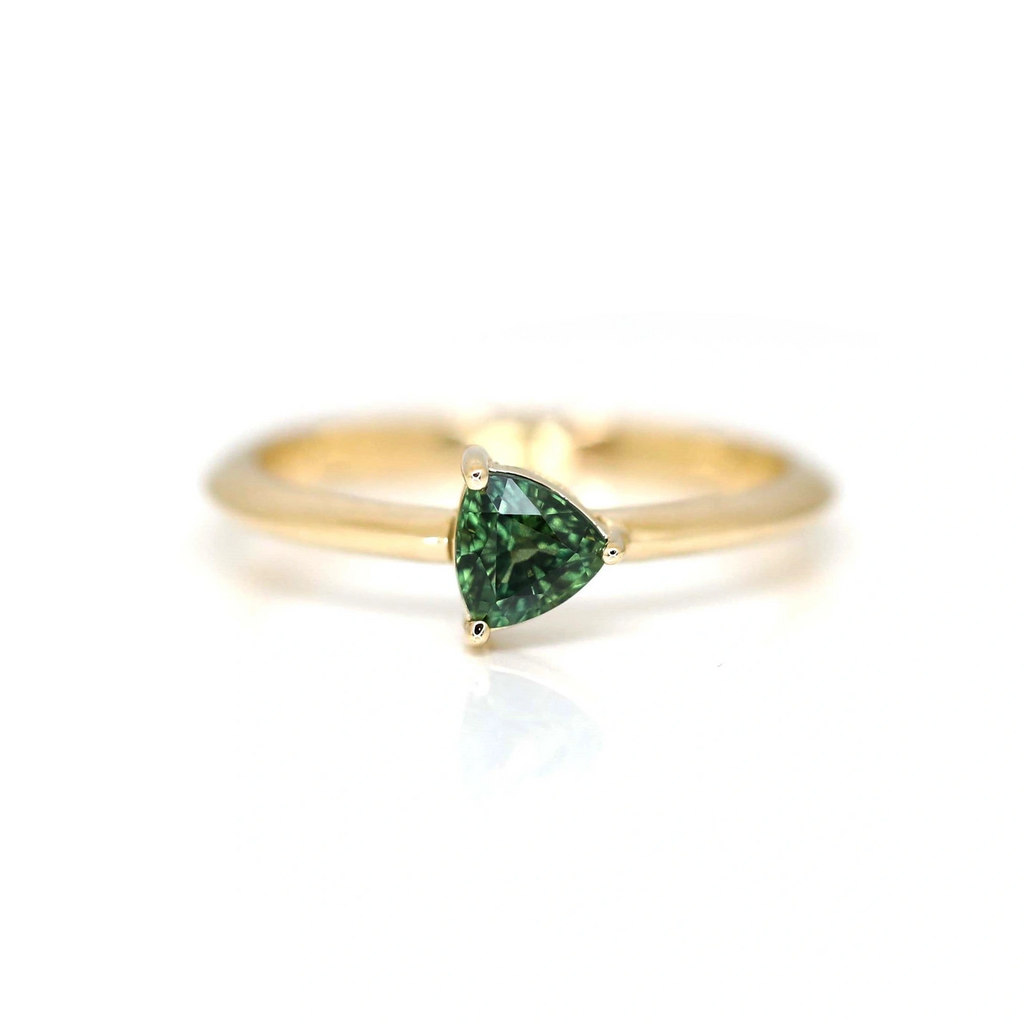 Minimalist engagement ring or right hand ring featuring a trillion-cut green sapphire set in yellow gold. Designed and handcrafted by Ruby Mardi in Montreal.