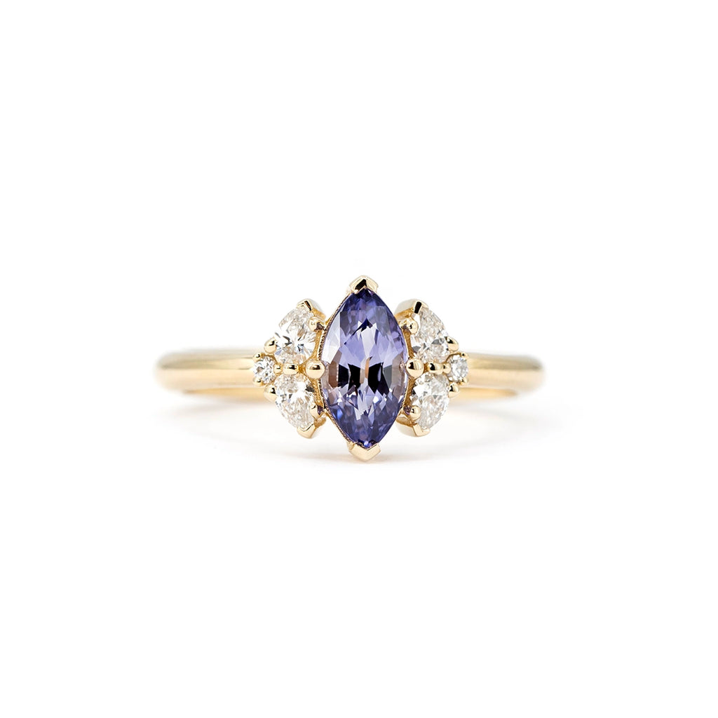 Gold engagement ring with a marquise-cut purple sapphire and side diamonds, set on a slim yellow gold band.