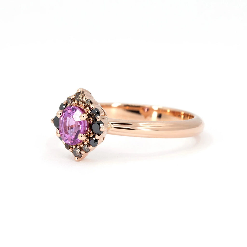 Rose gold engagement ring with oval pink sapphire and pointed halo of black and champagne diamonds. Designed and crafted by Ruby Mardi in Montreal.