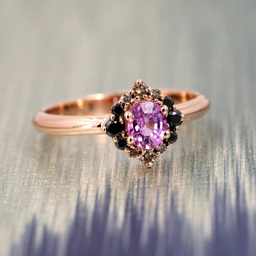 Velvet Aura engagement ring in rose gold, featuring a vivid oval pink sapphire surrounded by a pointed halo of black and champagne diamonds. Fine jewelry handcrafted in Montreal by Ruby Mardi.