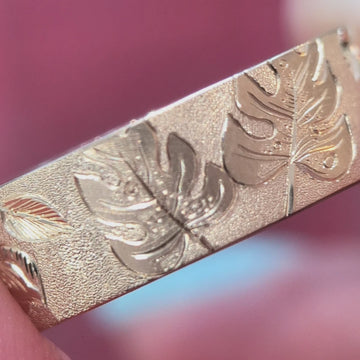 Video of a stunning hand-engraved 7 mm yellow gold band filmed with a macro lens on a pink background