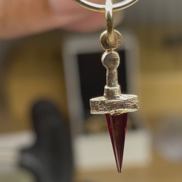 Macro video of the Hera claymore sword pendant in solid 14k gold with natural red garnet blade, showing movement and satin engraved finish, made in Montreal by Rosa Rvbea