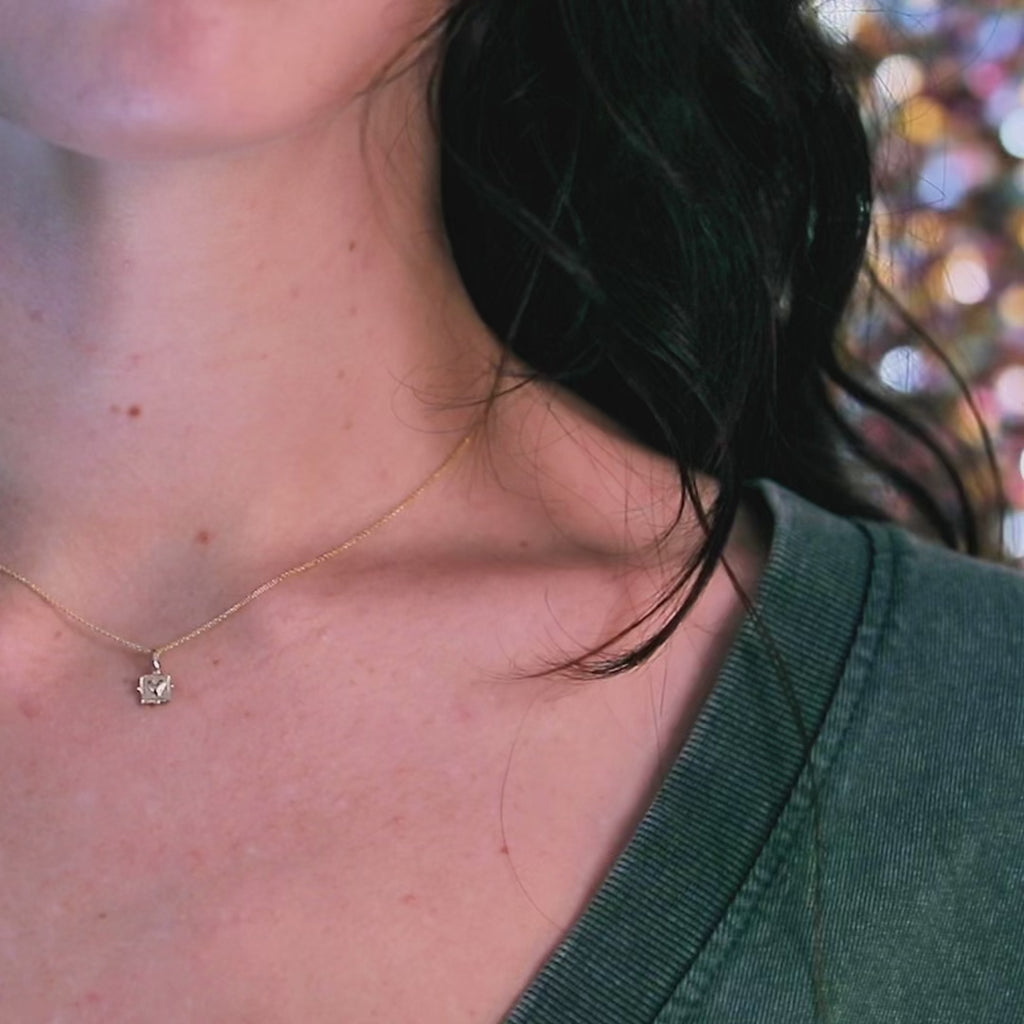 A video featuring a woman wearing a yellow gold pendant with a raised heart design. As she moves slowly, the pendant catches the light, highlighting its elegant shine. Designed by Emma Glover, available at Ruby Mardi, Montreal.